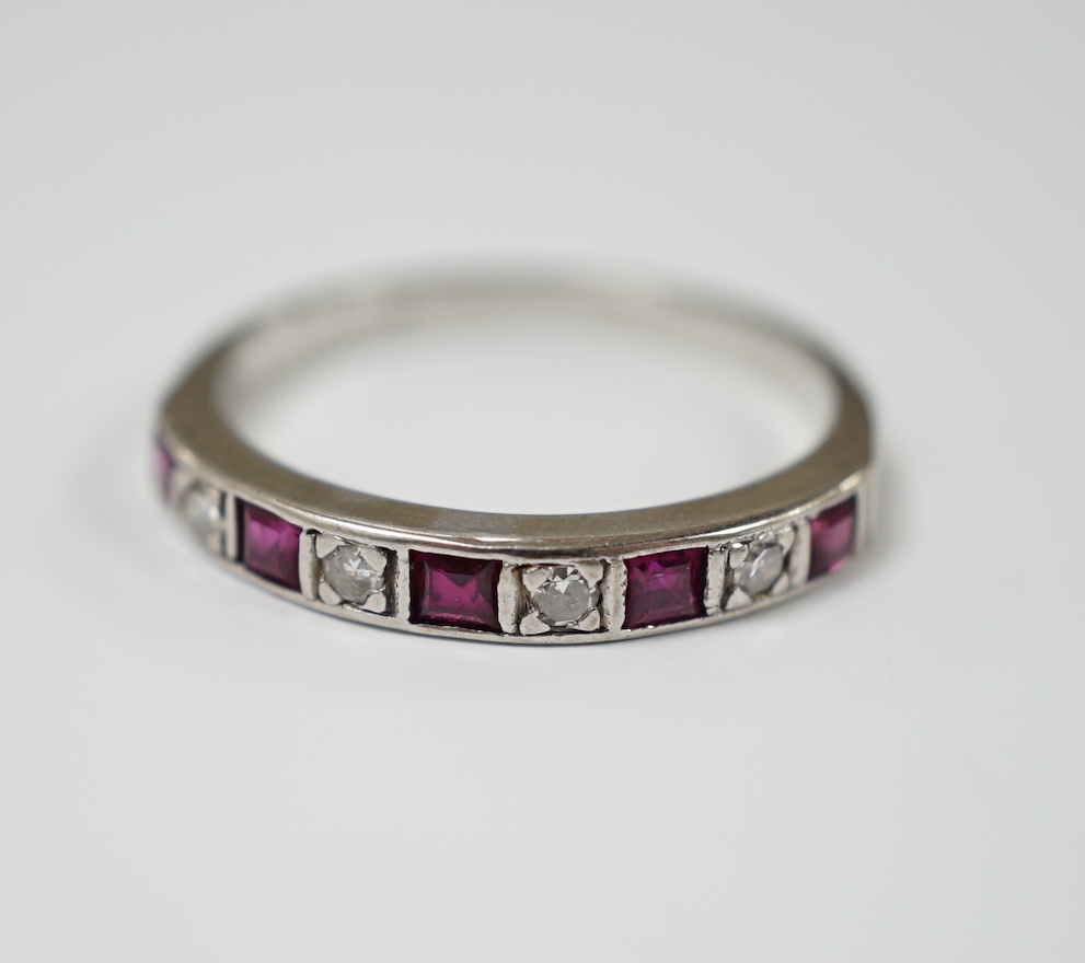 A modern 18ct white gold, ruby and diamond set half eternity ring, size O, gross weight 2.7 grams.